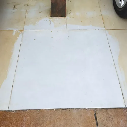 Calçada tomada pela ferrugem alaranjada com placa limpa revelada após aplicação do Eficaz Limpa Pisos